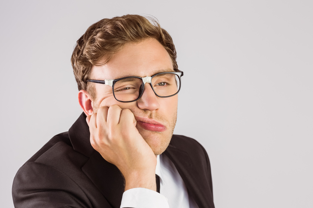 Young geeky businessman looking bored on grey background