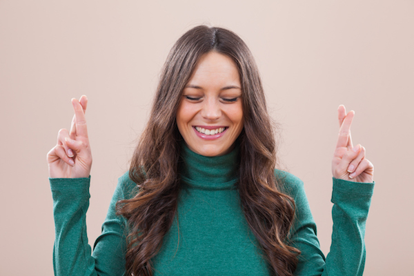 Portrait of happy woman with fingers crossed